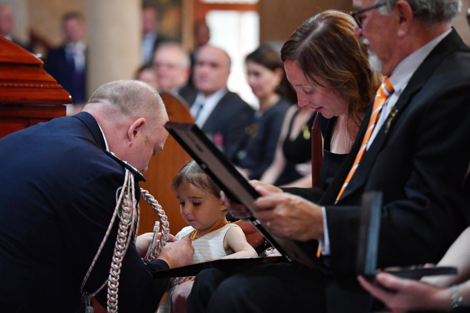 RFS Commissioner Shane Fitzsimmons pins her father's service medals to her dress at the funeral. Source: AAP