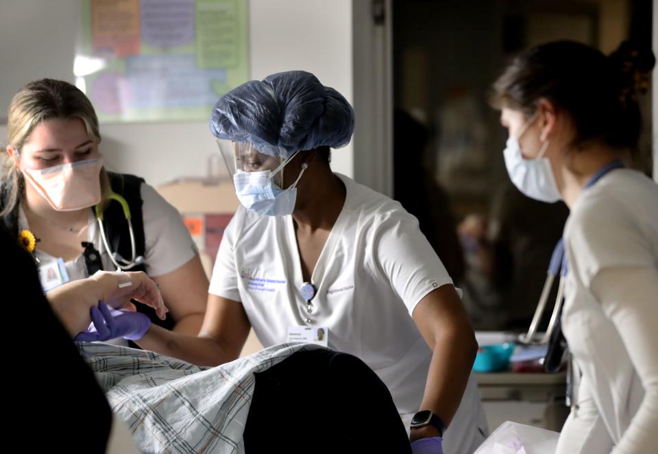 Vanessa Jean-Baptiste, center, a registered nurse in the intensive care unit at Northern Westchester Hospital in Mount Kisco, works with other nurses in transferring a new patient, whose COVID-19 status is uncertain, to a bed Feb. 28, 2022.