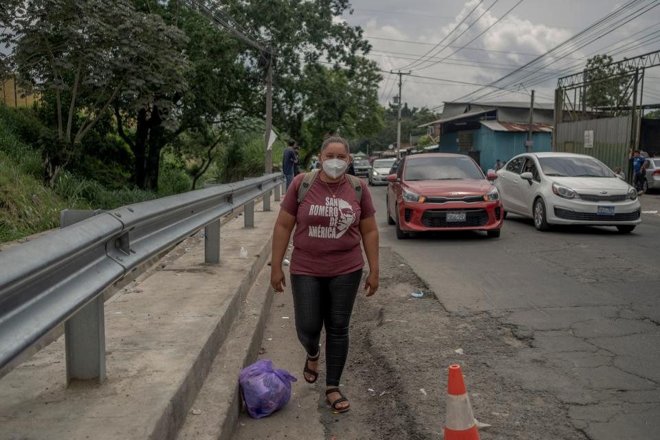 A woman is seen walking along a street as cars pass.