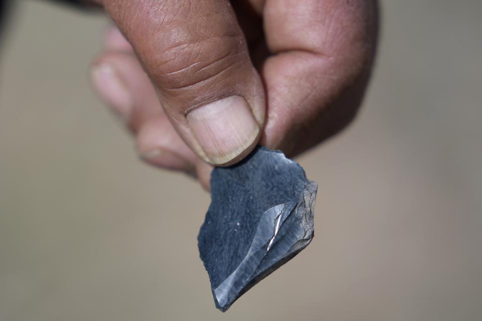 Myron Smart, a member of the Fort McDermitt Paiute and Shoshone tribe, displays a piece of obsidian, or volcanic rock, near Sentinel Rock on April 25, 2023, outside of Orovada, Nev. Similar rocks were used to make tools such as arrowheads or spearheads by Smart's ancestors. Pieces of obsidian rock can be found at Sentinel Rock, a sacred site for the Paiute and Shoshone tribes. (AP Photo/Rick Bowmer)