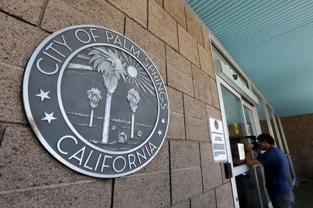 A member of the media takes photographs through the window outside Palm Springs City Hall during a federal raid on the city's offices in Palm Springs, California, September 1, 2015. REUTERS/Sam Mircovich