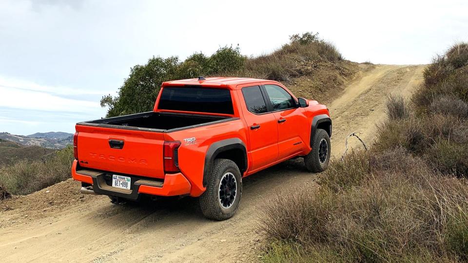 an orange 2024 toyota tacoma on a dirt road
