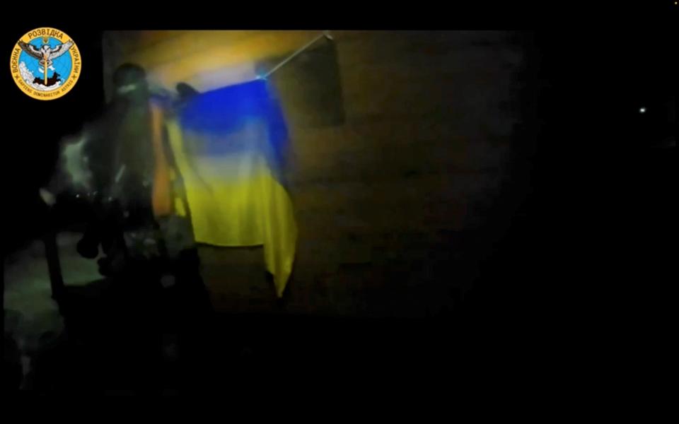 A Ukrainian soldier hangs a Ukrainian flag during a 'special operation' by Ukrainian forces at a location given as near Olenivka and Mayak settlements, Crimea, in this screengrab obtained from a handout video released on August 24, 2023.