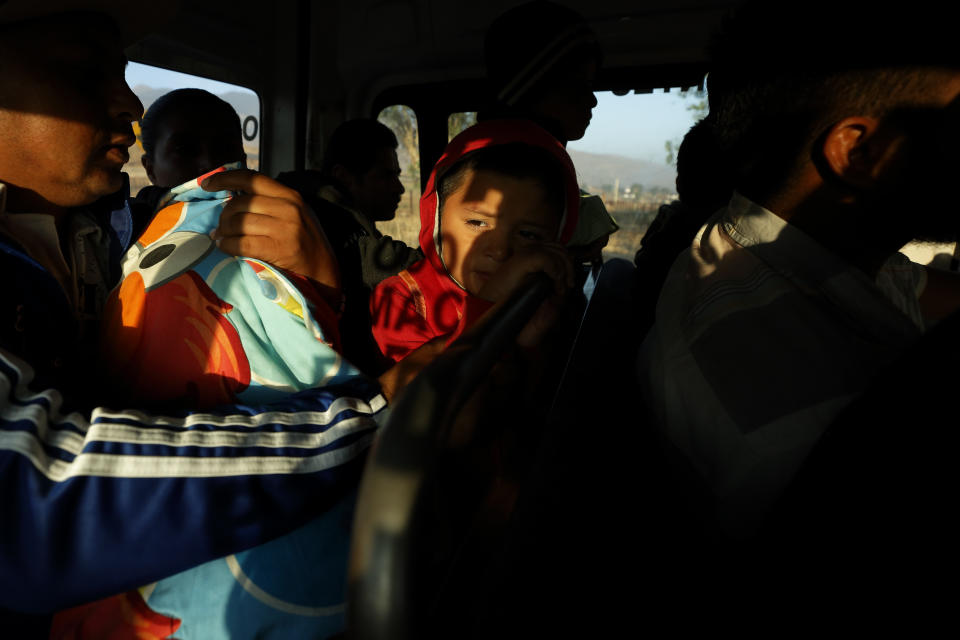 In this July 10, 2019, photo, Carlos Isai Perla looks out from a bus as he travels with his family from their home in Tijuana, Mexico, for an asylum hearing in San Diego. After fleeing violence in El Salvador, the family is among 60,000 U.S. asylum seekers returned to Mexico to wait while their claim makes its way through the U.S. court system. (AP Photo/Gregory Bull)