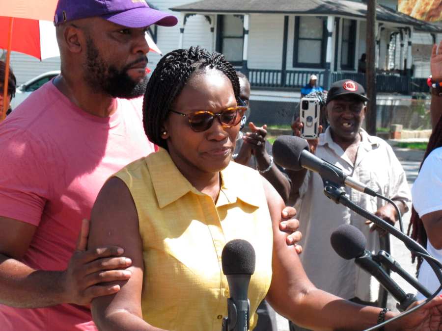 Wanda Cooper Jones, the mother of Ahmaud Arbery, is held by her attorney, Lee Merritt, while addressing supporters gathered for the unveiling of new street signs honoring Arbery on Tuesday, Aug. 9, 2022, in Brunswick, Ga. (AP Photo/Russ Bynum)