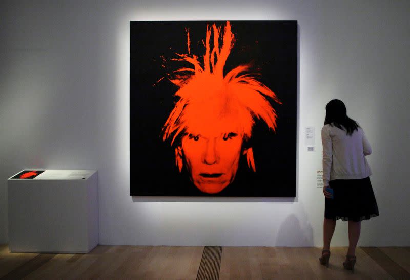 FILE PHOTO: A woman looks at a self portrait by Andy Warhol during the media preview of an exhibition on his works in Singapore