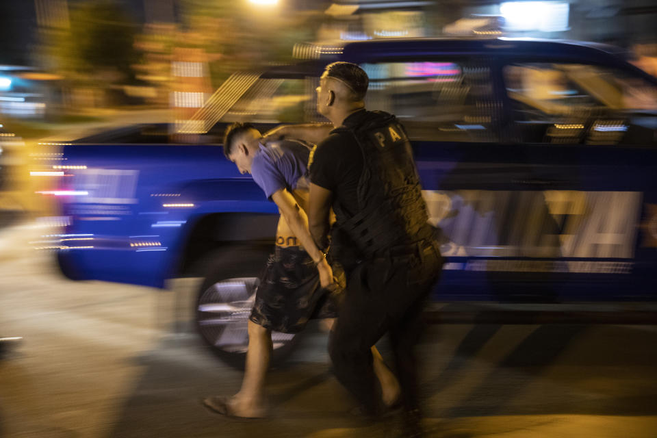 Police detain a man for suspected participation in the murder of a neighbor in Rosario, Argentina, Monday, Dec. 12, 2021. The city of some 1.3 million people has high levels of poverty and crime, where violence between gangs who seek to control turf and drug markets has helped fill its prisons. (AP Photo/Rodrigo Abd)