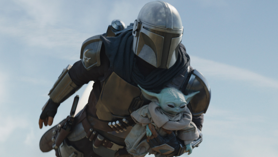 The Mandalorian flies while carrying Baby Yoda, a.k.a. Grogu.