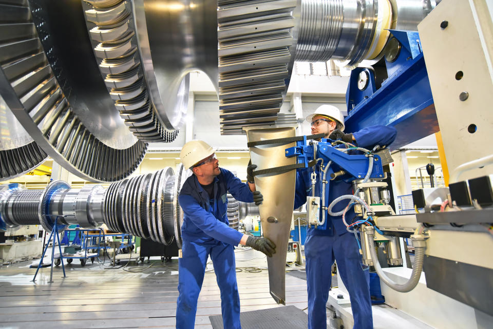 workers assembling and constructing gas turbines in a modern industrial factory