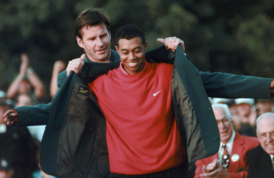 FILE - In this April 13, 1997, file photo, Masters champion Tiger Woods receives his Green Jacket from last year's winner Nick Faldo, left, at the Augusta National Golf Club in Augusta, Ga. There is no Masters this year because of the COVID-19 pandemic, the first time there is no golf at Augusta National the first full week in April since the end of World War II in 1945. (AP Photo/ Dave Martin, File)