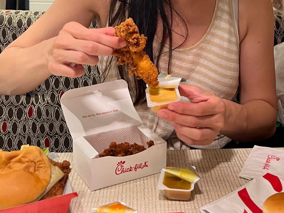 tiffany dipping a chicken strip into dipping sauce at chick fil a