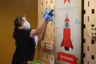 Corina Guerra cleans an interactive display at Science Museum Oklahoma, Monday, June 1, 2020, in Oklahoma City as the museum reopens with limited capacity and social distancing requirements. Employees are required to wear masks and guests are encouraged to wear masks. (AP Photo/Sue Ogrocki)