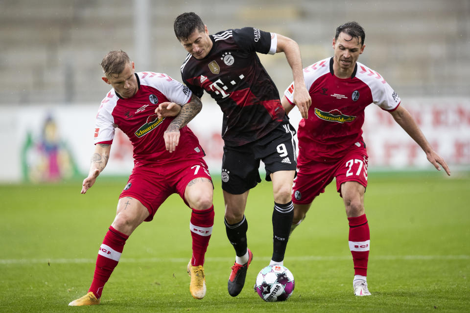 Robert Lewandowski del Bayern Munich, centro, se lleva el balón entre Nicolas Hoefler, derecha y Jonathan Schmid en partido de la Bundesliga entre Freiburg y Bayern en Freiburg, Alemania, sábado 15 de mayo de 2021. Lewandowski anotó su gol nímero 40 en la temporada, igualando el viejo récord de Gerd Müller. (Tom Weller/dpa via AP)