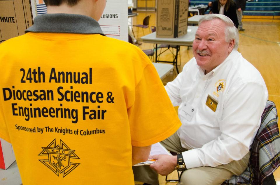 Joe Hudak of the Knights of Columbus welcomes an attendee at the Knights’ sponsored science and engineering fair | Andy Airriess