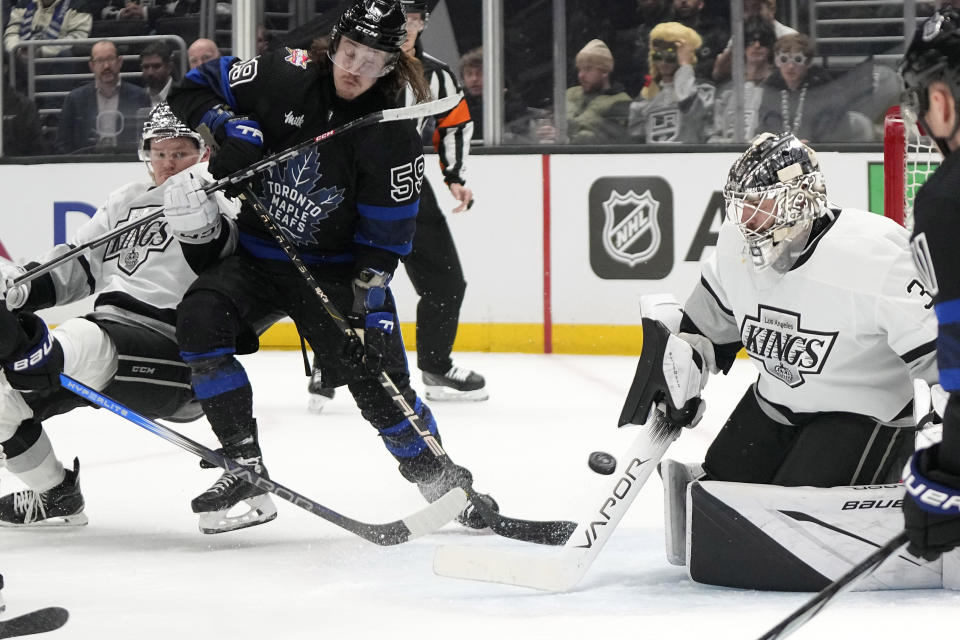 Los Angeles Kings goaltender Cam Talbot, right, stops a shot as defenseman Mikey Anderson, left, defends against Toronto Maple Leafs left wing Tyler Bertuzzi during the first period of an NHL hockey game Tuesday, Jan. 2, 2024, in Los Angeles. (AP Photo/Mark J. Terrill)