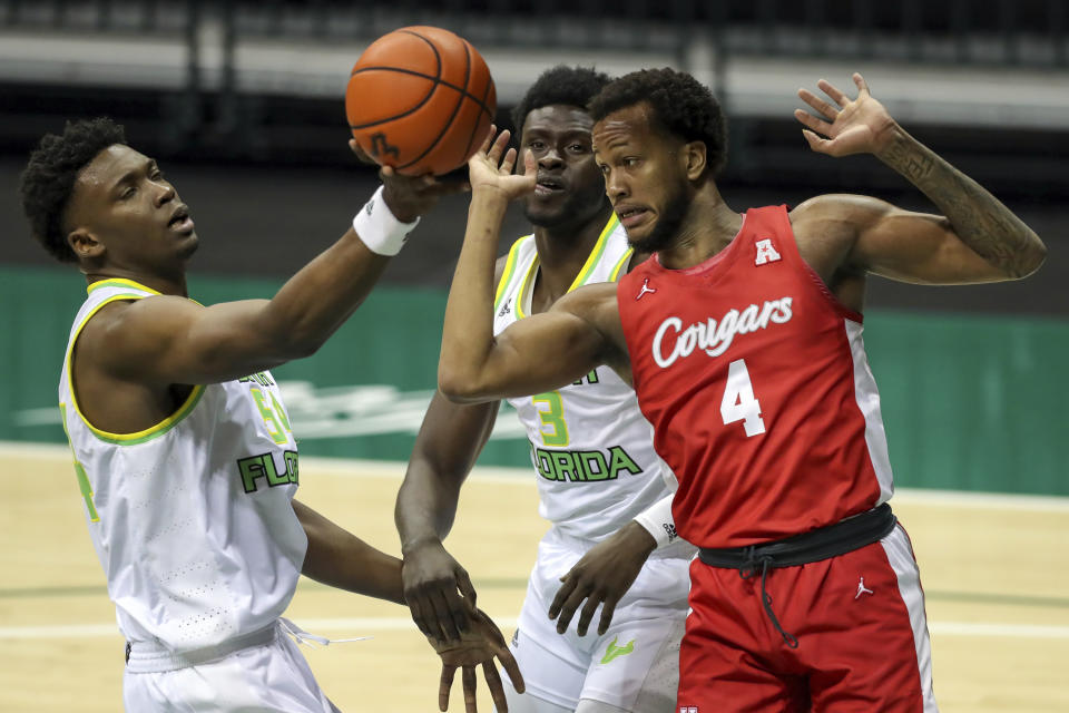 South Florida's Russel Tchewa, left, grabs a rebound in front of Houston's Justin Gorham (4) as South Florida's Prince Oduro (3) looks on during the first half of an NCAA college basketball game Wednesday, Feb. 10, 2021, in Tampa, Fla. (AP Photo/Mike Carlson)