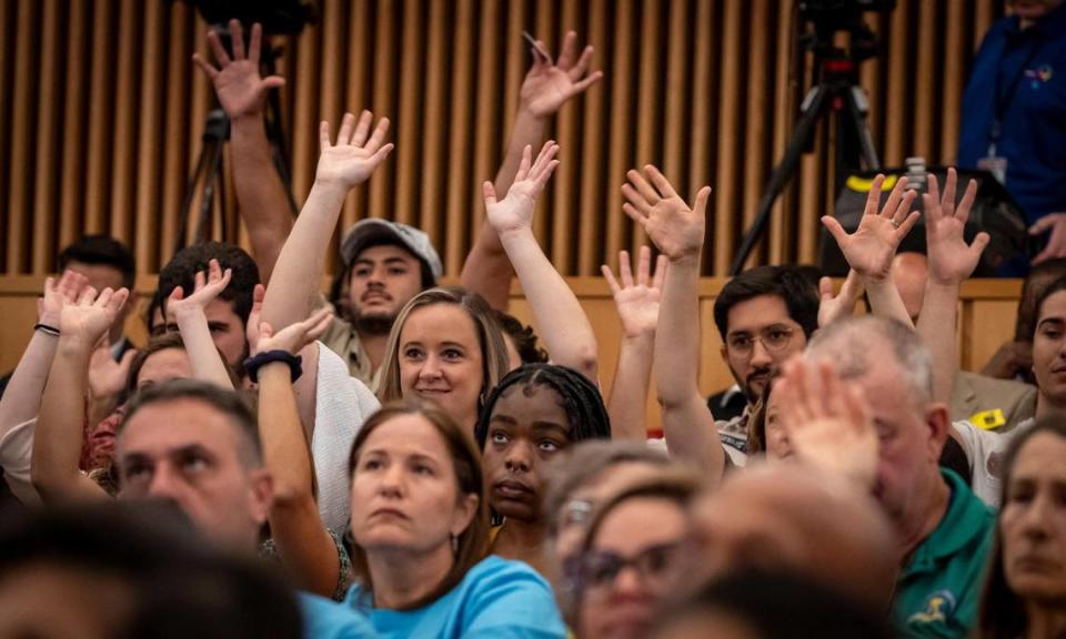 People wave their hands in support of speakers voicing opposition to Miami Wilds water park during the public comment portion of the Miami-Dade County Commission meeting on Wednesday, Sept. 6, 2023. A planned vote was delayed, and it’s now slated for Dec. 12.