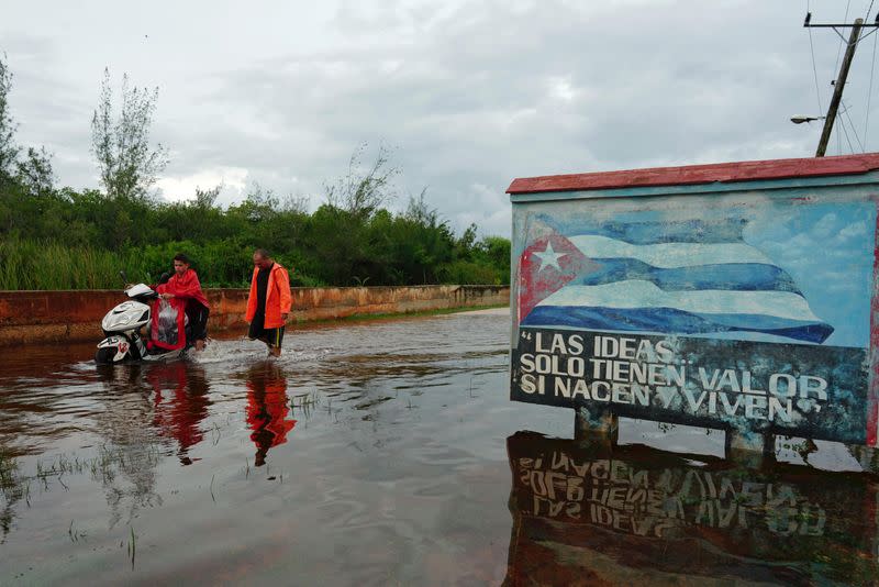 La gente camina por una calle inundada mientras la tormenta Idalia toca tierra en Guanimar