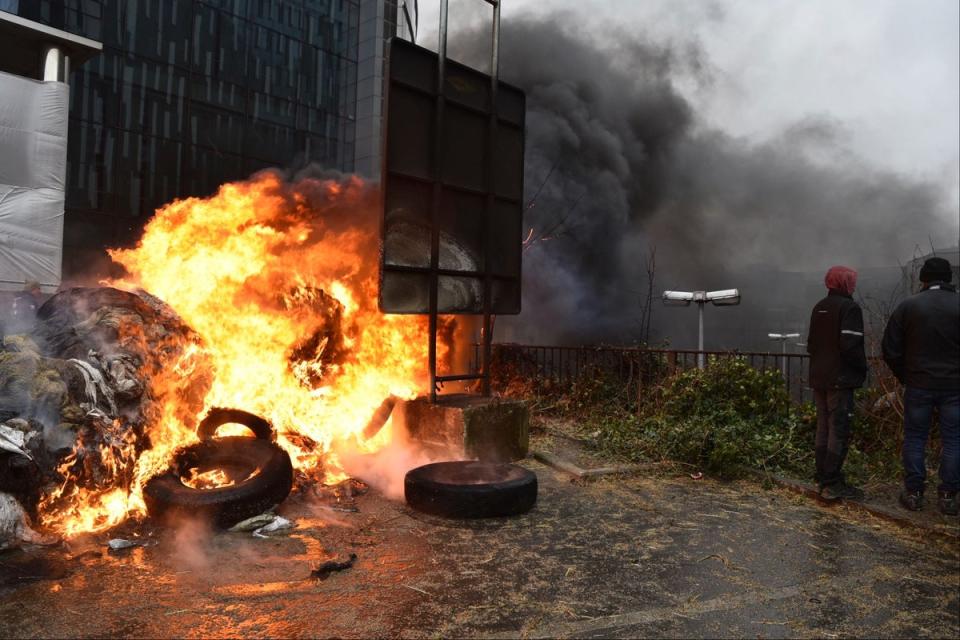 Protestors light fires during a farmers’ demonstration in Brussels on Monday (AP)