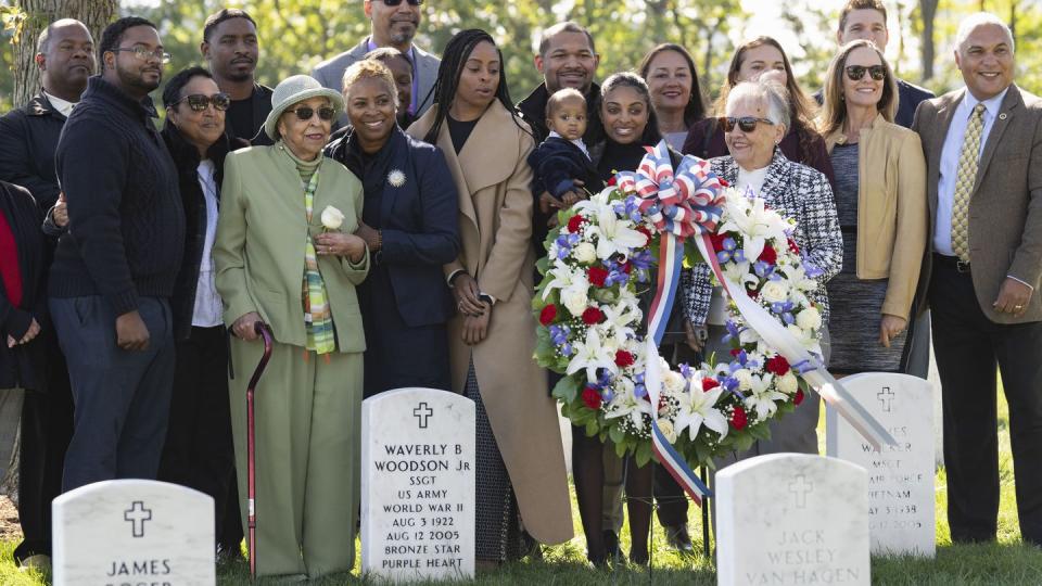 Joann Woodson, in green, is joined by family at the headstone of her husband, Cpl. Waverly B. Woodson Jr., following a ceremony at Arlington National Cemetery on Tuesday, Oct. 11, 2023 in Arlington, Va. (Kevin Wolf/AP)