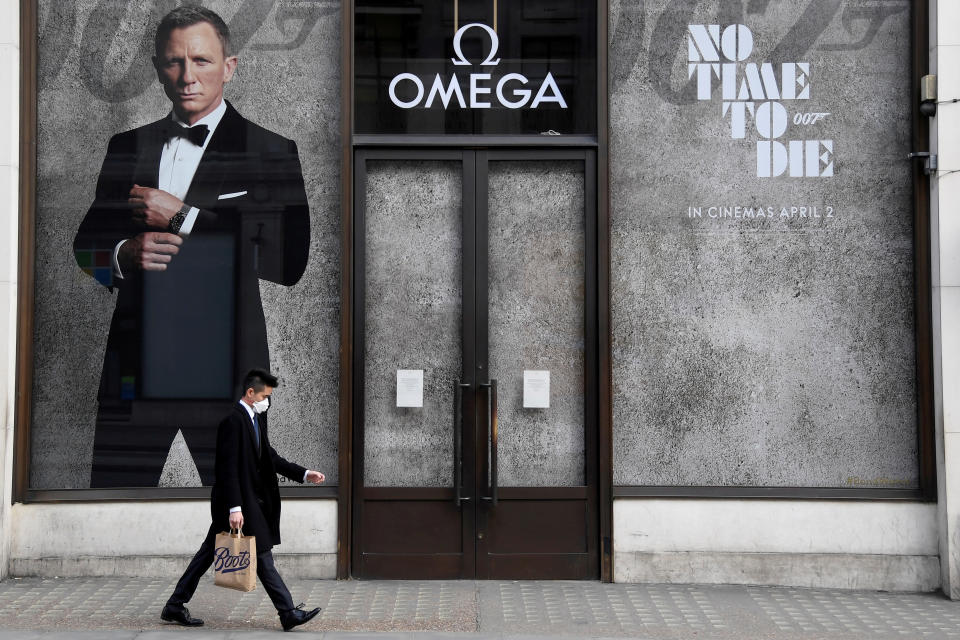 A man walks past a shop promoting the new James Bond film No Time To Die in London on 20 March 2020 as the coronavirus spread. It had originally been due for release on 2 April 2020