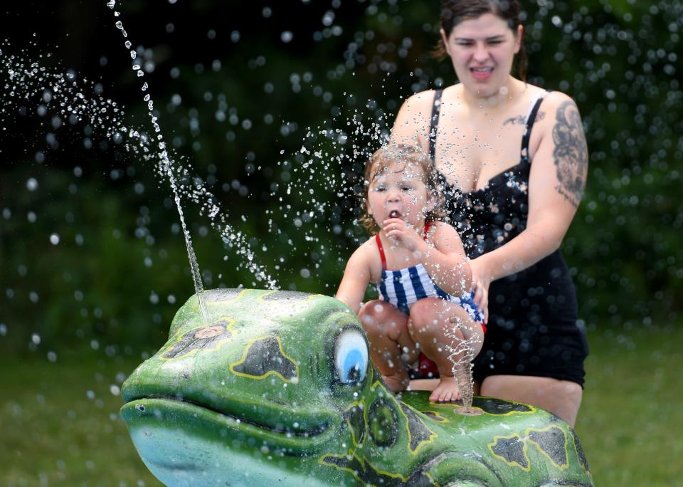 Raine Barnett, 3, with mom, Cheyenne Mick of East Canton stay cool on a hot summer day on the splash pad at Plain Township Veterans Park.