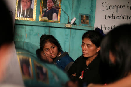 A girl lays her face on the coffin of Misael Paiz, 25, below his photos inside his family home at a wake in Aguacate, Huehuetenango, Guatemala, October 29, 2018. REUTERS/Lucy Nicholson