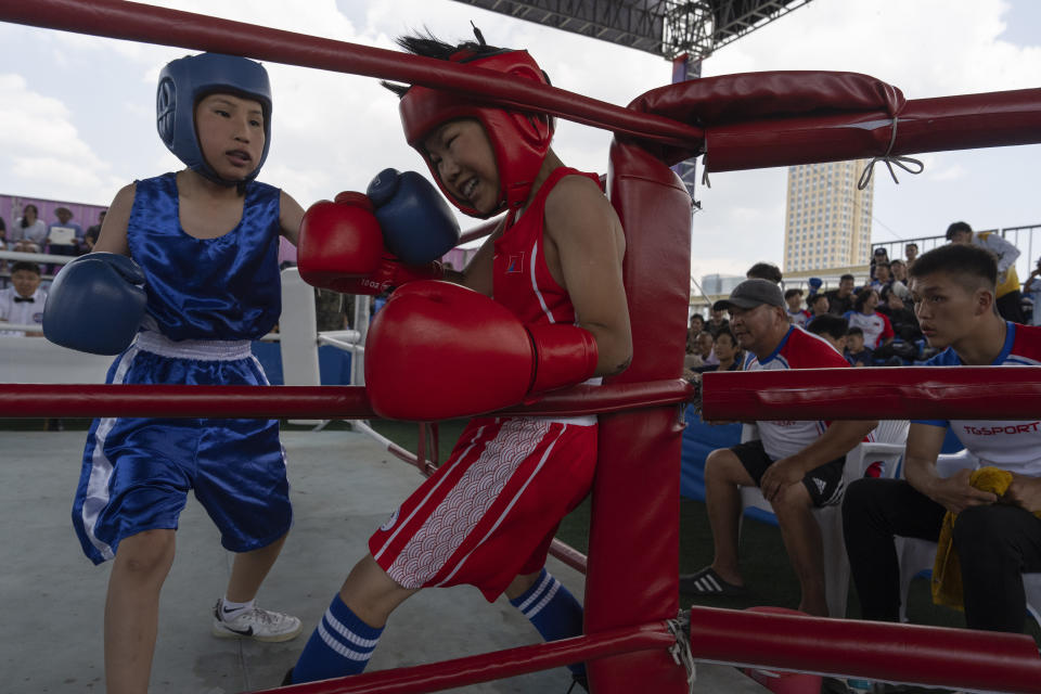 Twelve-year-old Gerelt-Od Kherlen, in red, defends against an attack from his opponent during a bronze medal boxing match on Sukhbaatar Square in Ulaanbaatar, Mongolia, Tuesday, July 2, 2024. Growing up in a Ger district without proper running water, Gerelt-Od fetched water from a nearby kiosk every day for his family. Carrying water and playing ball with his siblings and other children made him strong and resilient. (AP Photo/Ng Han Guan)