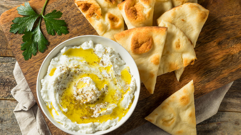 labneh dip with pita on wooden cutting board and counter