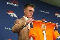 Denver Broncos first-round selection in the NFL football draft quarterback Bo Nix looks over a jersey after a news conference Friday, April 26, 2024, at the team's headquarters in Centennial, Colo. (AP Photo/David Zalubowski)