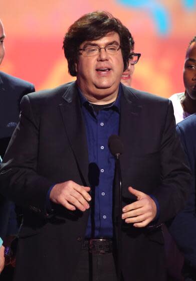 Dan Schneider at a microphone on stage.