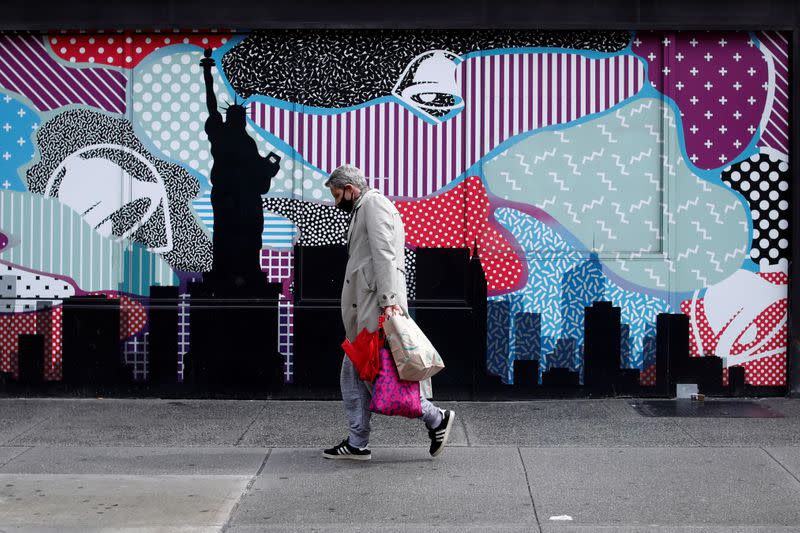 A man wears a protective face mask as he walks past closed stores in Manhattan during the outbreak of the coronavirus disease (COVID-19) in New York