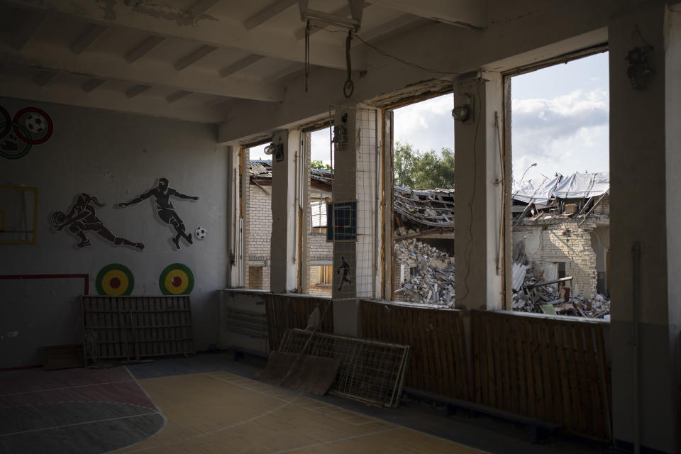 The destroyed library of a school is seen through the broken windows of a gym in Kupiansk, Ukraine, Wednesday, Aug. 23, 2023. (AP Photo/Bram Janssen)