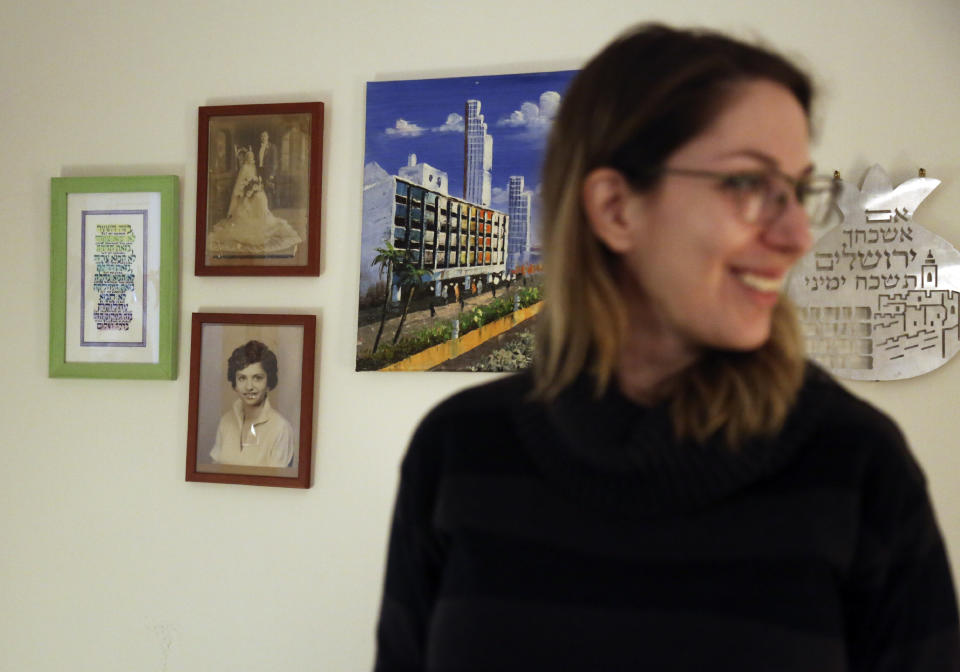 In this Friday, Jan. 3, 2020, photo, Jewish grandparents, prayers and a painting of Tel Aviv are seen on a wall in Alexandra Cohen's apartment in New York. Cohen, who regularly prepares Shabbat dinner for her Jewish friends, says, "I’ve kind of chosen a path that's not directly combating the BDS and the anti-Semitism, partially because I fear for my own security, and partially because I feel that exposing the positive side of Jewish life and contemporary Jewish society, is the way that it’s going to be perpetuated." (AP Photo/Jessie Wardarksi)