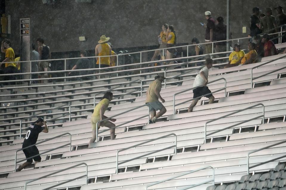 Fans flee for cover during a monsoon storm at the Arizona State Sun Devils home opener against the Southern Utah Thunderbirds at Mountain America Stadium in Tempe on Aug. 31, 2023.