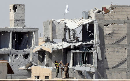 Fighters of Syrian Democratic Forces raise a white flag near the National Hospital complex where the Islamic State militants are holed up, at the frontline in Raqqa, Syria. REUTERS/Erik De Castro