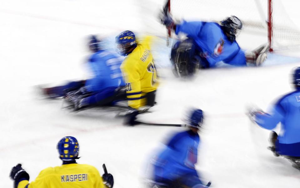 Niklas Rakos, center, of Sweden, celebrates as Per Kasperi, left, scores a goal during an ice sledge hockey match against Italy at the 2014 Winter Paralympics in Sochi, Russia, Wednesday, March 12, 2014. Italy won 3-2. (AP Photo/Pavel Golovkin)