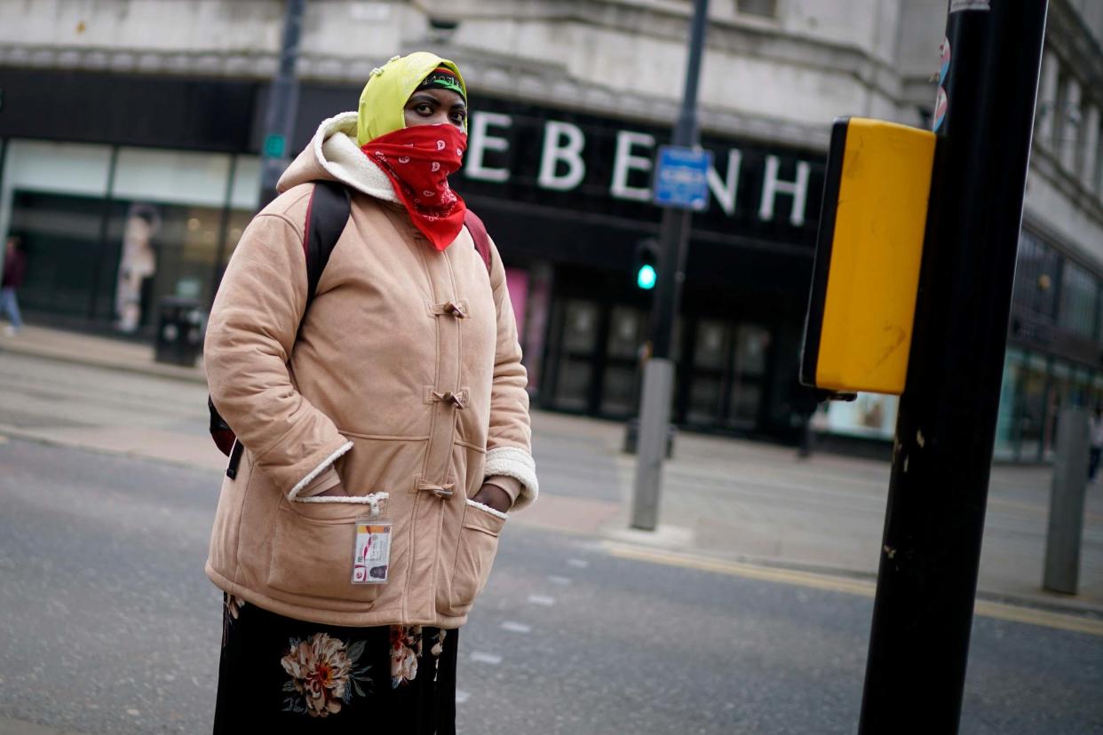 A woman wearing a scarf for protection walks through Manchester City centre: Getty Images