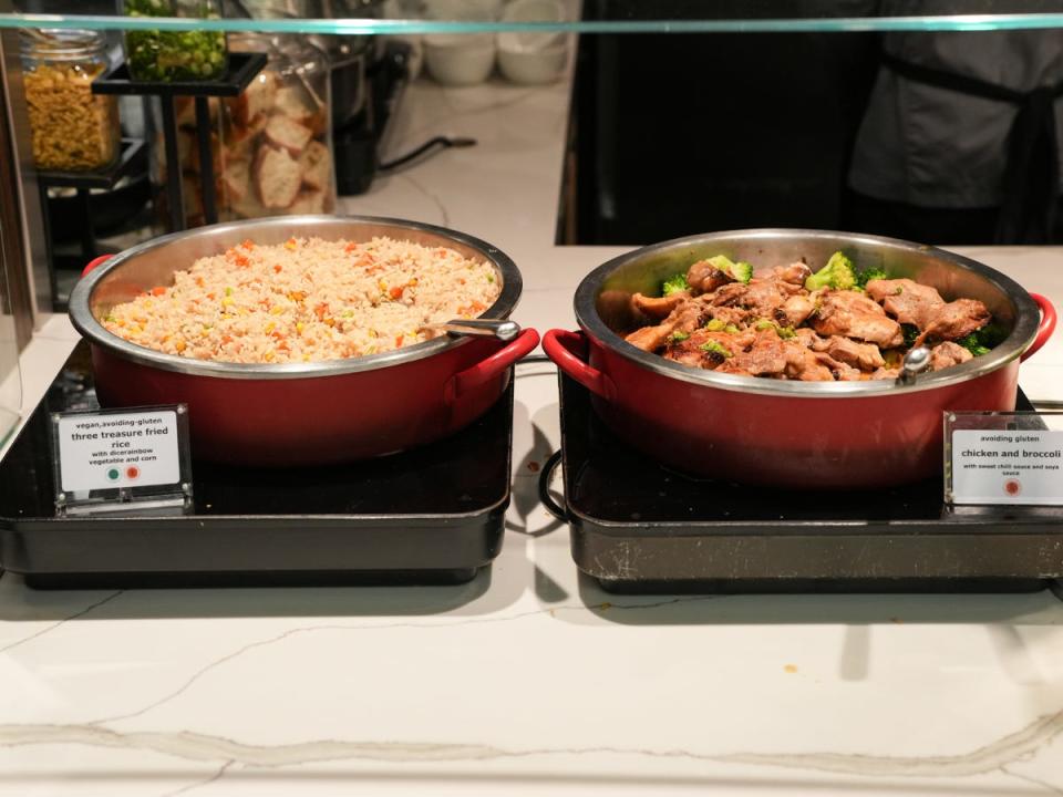 Two red bowls of food behind a clear window. One pot is filled with three-treasure fried rice and the other has chicken and broccoli