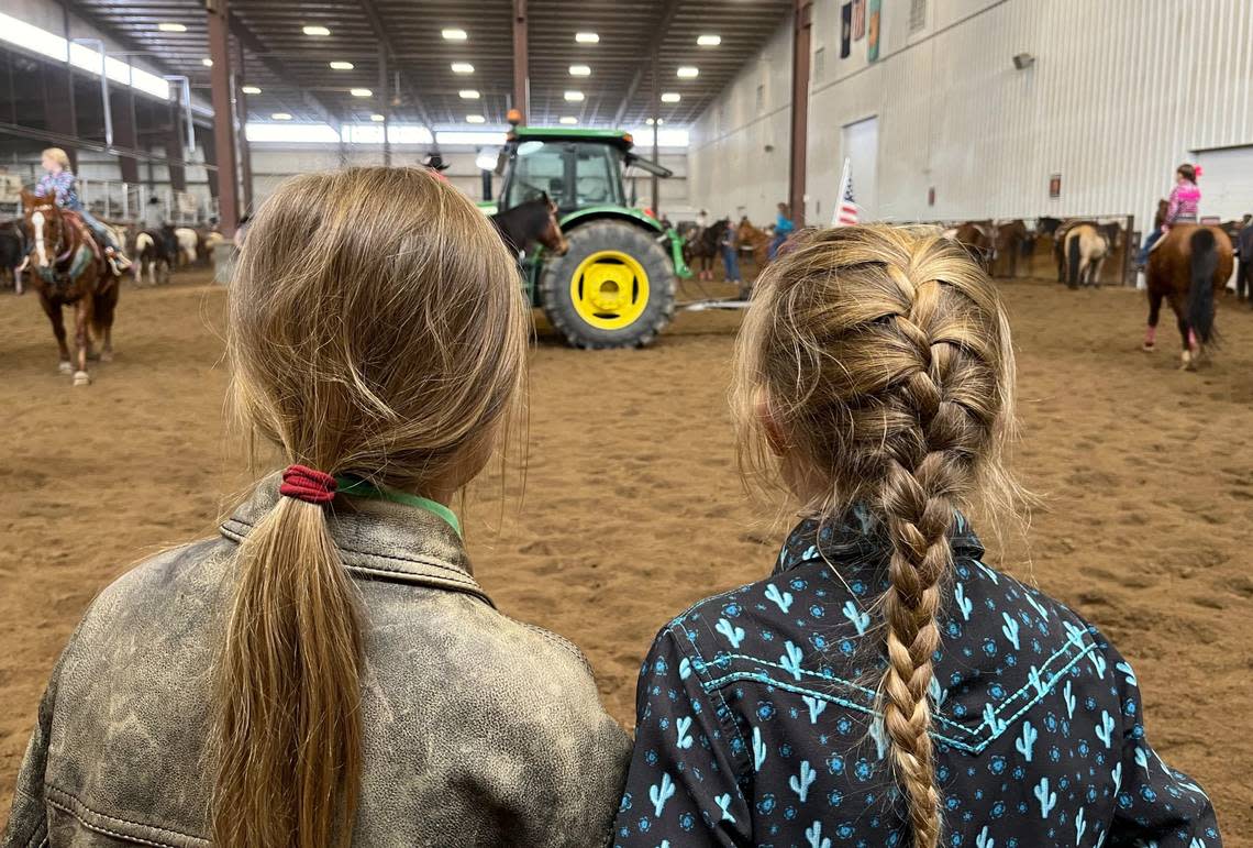 Nine-year-olds Paisley Davis, left, and Braylin Barratt watch other rodeo competitors warm up their horses between events at the Young Guns Extravaganza in Dodge City. This youth rodeo has seen explosive growth since it began eight years ago.