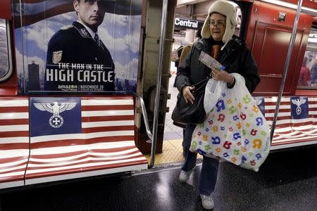 Passengers board a 42nd Street Shuttle subway train, wrapped with advertising for the Amazon series "The Man in the High Castle" in Manhattan, New York, November 24, 2015. REUTERS/Brendan McDermid