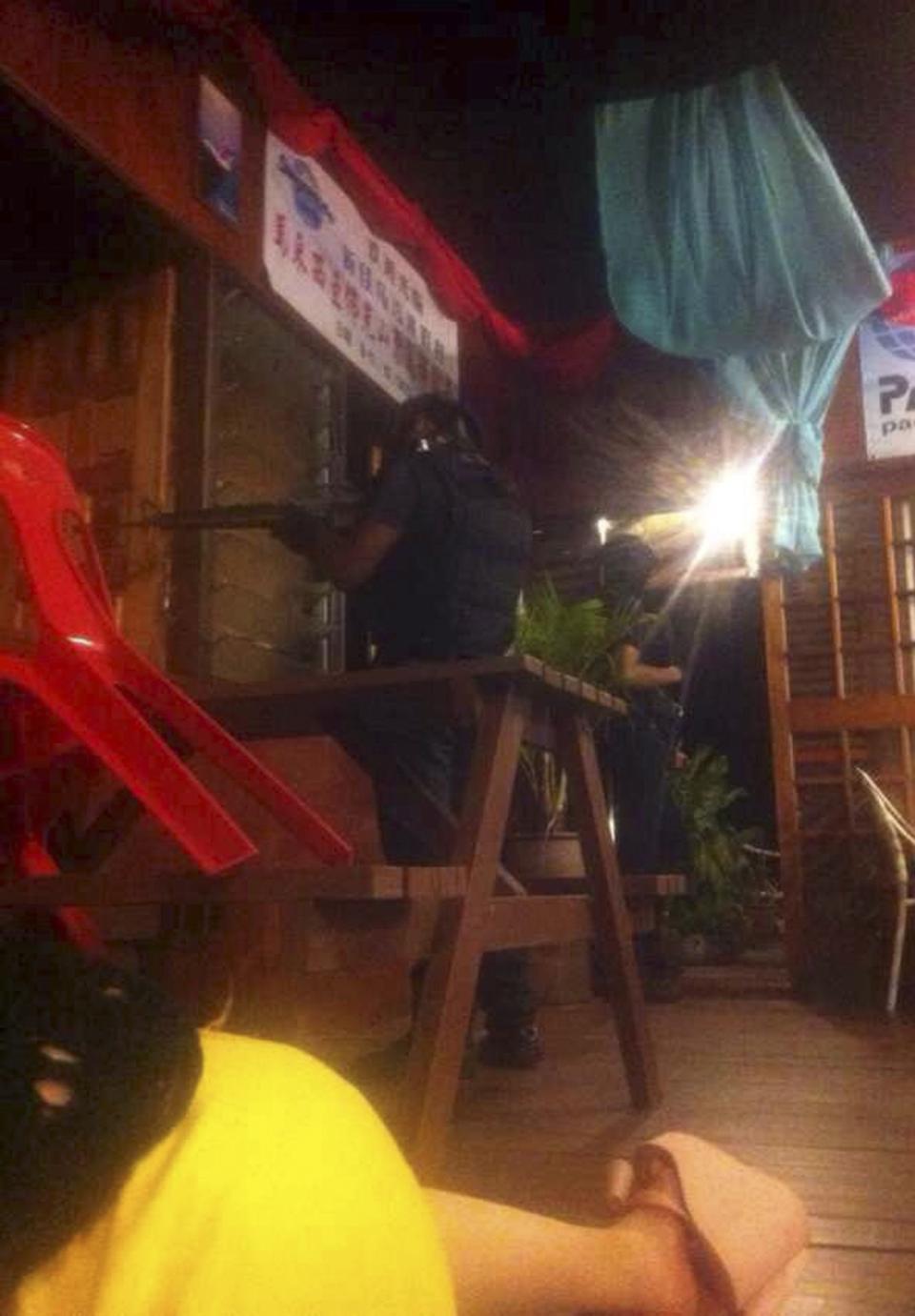 Armed men are seen near a door of a hotel as tourists take shelter on the floor in Sabah