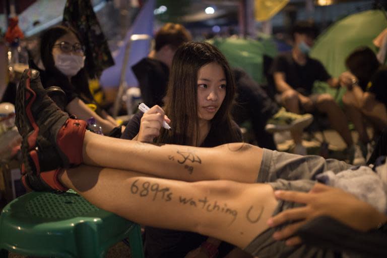 A pro-democracy protester writes slogans on the leg of a colleague as they occupy the Admiralty district of Hong Kong, early on October 7, 2014