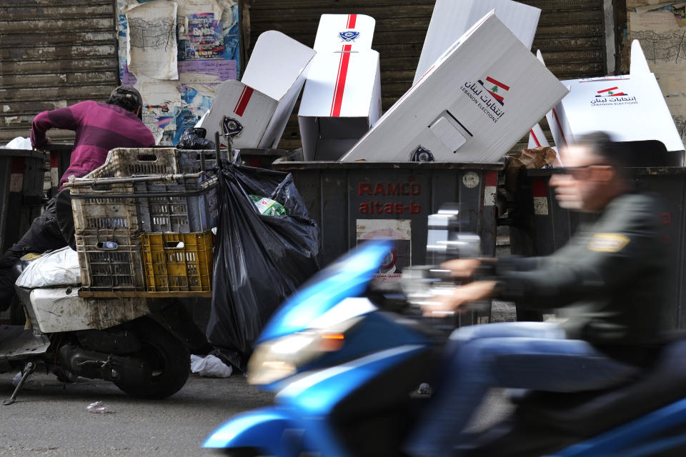 A man searches in trash dumpsters for recyclable items to resell next to voting booths that were used Sunday in the Lebanese parliamentary elections, in Beirut, Lebanon, Monday, May 16, 2022. Lebanon's militant Hezbollah group and its allies suffered losses in this weekend's parliamentary elections, with preliminary results Monday showing some of their most vocal opponents picking up more seats and several of their traditional partners routed out of the legislature. (AP Photo/Hassan Ammar)