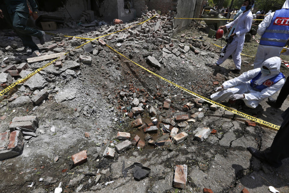 Investigators collect evidence at the site of explosion, in Lahore, Pakistan, Wednesday, June 23, 2021. A powerful explosion ripped through a residential area in the eastern city of Lahore on Wednesday, killing some people and injuring some others, police and rescue officials said. (AP Photo/K.M. Chaudary)