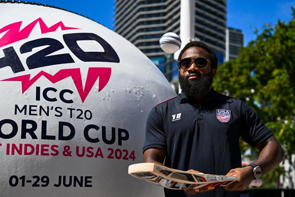 USA Cricket Vice-Captain Aaron Jones taps a ball with a bat next to a giant cricket ball installed at a marketplace to mark 100 days to go for the ICC Men's T20 World Cup in Miami, Florida, on February 22, 2024.