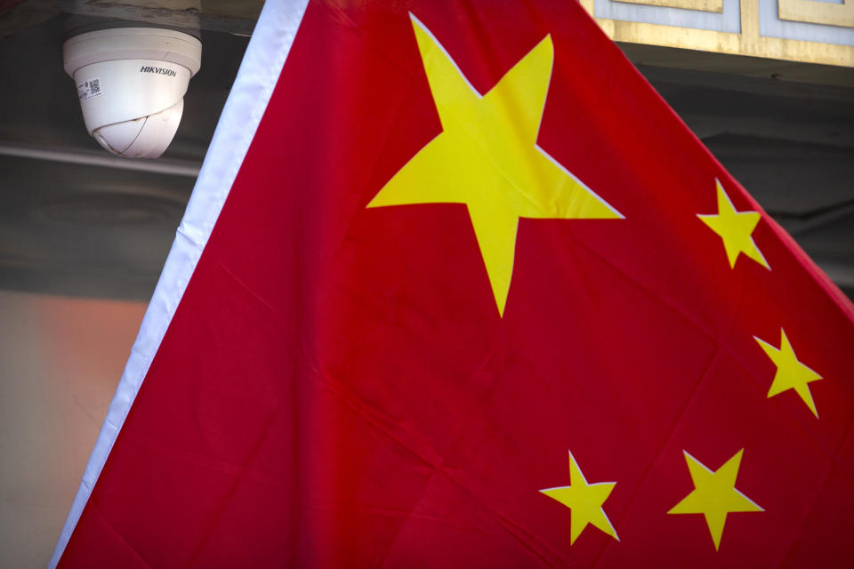 A Chinese flag hangs near a Hikvision security camera outside of a shop in Beijing, Tuesday, Oct. 8, 2019. The United States is blacklisting a group of Chinese tech companies that develop facial recognition and other artificial intelligence technology that the U.S. says is being used to repress China's Muslim minority groups. (AP Photo/Mark Schiefelbein)