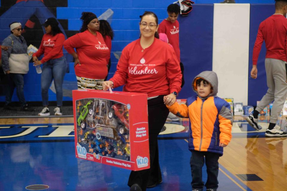 A volunteer helps a child carry his new toy Saturday at the 10th annual Northside Toy Drive held at the Palo Duro High School Gym in Amarillo.