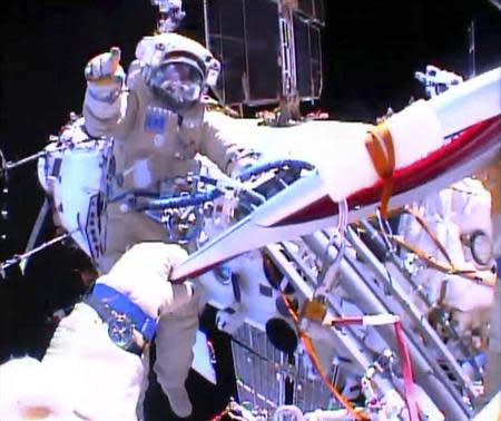 Russian astronaut Oleg Kotov holds an Olympic torch as he takes it on a spacewalk as Russian astronaut Sergei Ryazansky gives instructions outside the International Space Station in this still image taken from video courtesy of NASA TV, November 9, 2013. REUTERS/NASA TV/Handout via Reuters