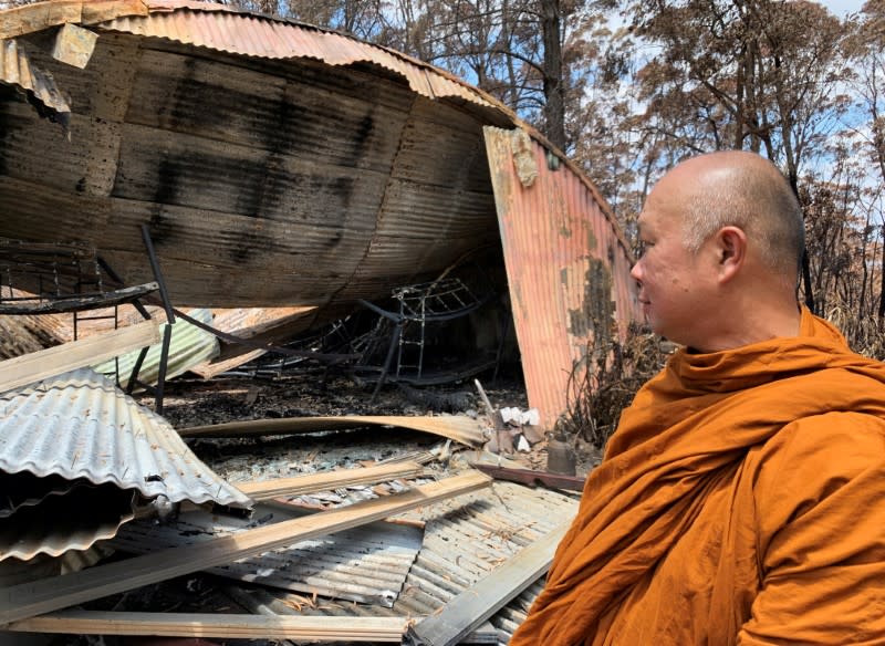 The Abbot of Sunnataram Forest Monastery, Phra Mana, 56, looks at the ruins of a burnt female dormitory in Bundanoon, Australia